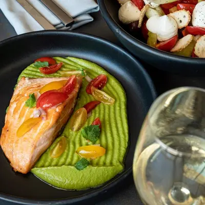 a plate of food with a piece of fish and a salad at Somewhere Vouliagmeni in Athens