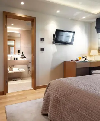 a bedroom with a bed and a television on a wall at Somewhere Vouliagmeni in Athens