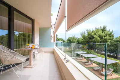 a balcony with glass railing and a table and chairs at Somewhere Vouliagmeni in Athens