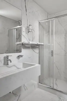 a bathroom with a shower and a sink and a mirror at Athos Hotel in Athens