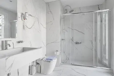 a white bathroom with a shower and a sink at Athos Hotel in Athens