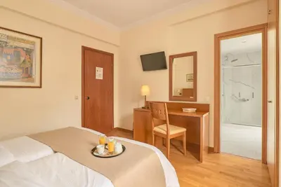 a hotel room with a bed and a desk with a plate on it at Athos Hotel in Athens