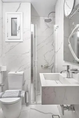 a white bathroom with a toilet and a sink at Athos Hotel in Athens