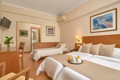 a hotel room with two beds and a table at Athos Hotel in Athens