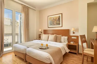 a hotel room with a large bed and a desk at Athos Hotel in Athens