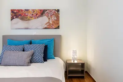 a bedroom with a bed with blue pillows and a painting at Acropolis Boutique Suite in Athens