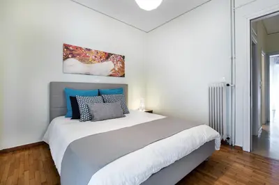 a white bedroom with a large bed with blue pillows at Acropolis Boutique Suite in Athens