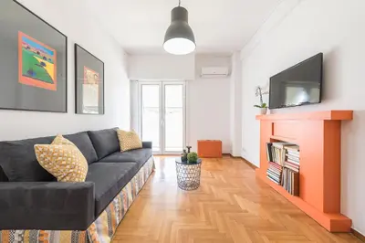 a living room with a black couch and a tv at New Relaxed Central Apartment Walk Everywhere in Athens