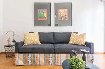a blue couch in a living room with pictures on the wall at New Relaxed Central Apartment Walk Everywhere in Athens