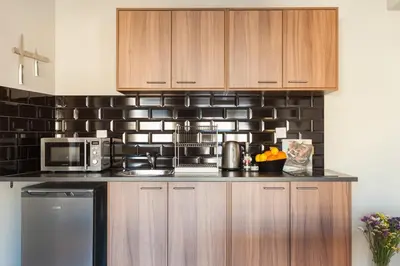 a kitchen with wooden cabinets and a black brick wall at Amazing Penthouses with Acropolis View in Athens