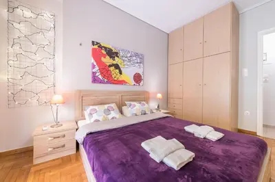 a bedroom with a large purple bed with two towels at Zenios Ippokratis-Comfort & style, Athens downtown in Athens