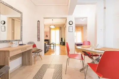 a living room with a dining table and red chairs at Zenios Ippokratis-Comfort & style, Athens downtown in Athens