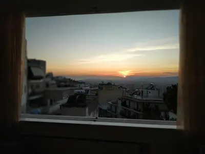 a view of a sunset from a window at Private pool & Panorama View on Athens center Hill in Athens