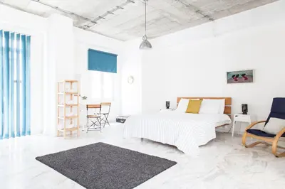 a white bedroom with a bed and a chair at Concierge Downtown in Athens