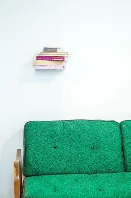 a green couch with a stack of books on a wall at Concierge Downtown in Athens