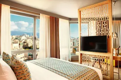 a hotel room with a bed and a large window at Zeus Wyndham Grand Athens in Athens