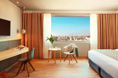 a hotel room with a bed and a desk and a window at Zeus Wyndham Grand Athens in Athens