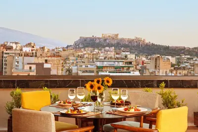 a table with plates of food and wine glasses at Zeus Wyndham Grand Athens in Athens