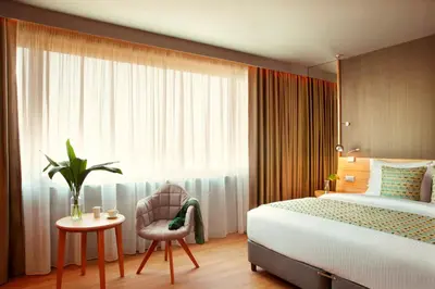 a bedroom with a bed and a chair and a window at Zeus Wyndham Grand Athens in Athens