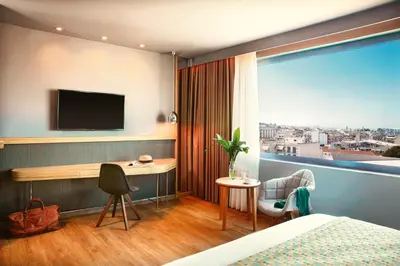 a hotel room with a bed and a desk and a window at Zeus Wyndham Grand Athens in Athens