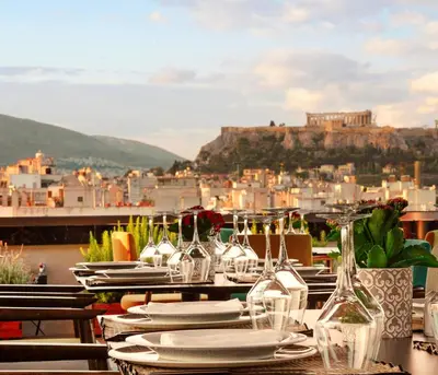 a table with plates and wine glasses on a balcony at Zeus Wyndham Grand Athens in Athens