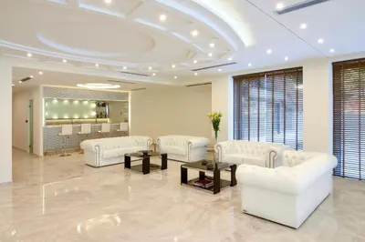 a lobby with white couches and tables and windows at Athens Avenue Hotel in Athens