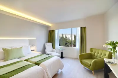 a bedroom with a large bed and a green chair at Athens Avenue Hotel in Athens
