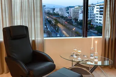 a chair and a glass table in a room with a window at Athens Avenue Hotel in Athens