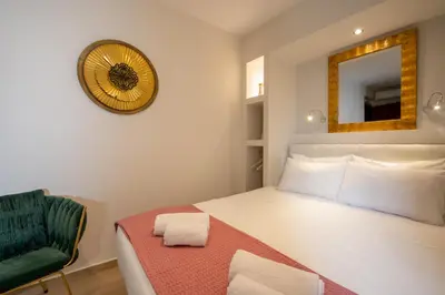 a bedroom with a bed and a mirror and a chair at Dema Luxury Suites - Perikleous E1 in Athens