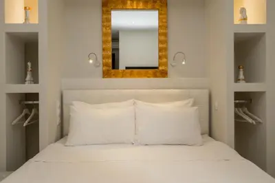 a bedroom with a white bed with a mirror above it at Dema Luxury Suites - Perikleous E1 in Athens