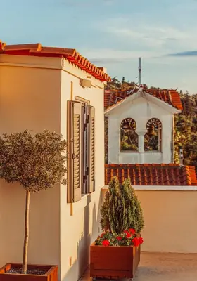 a white building with two potted plants and a house at Suitas in Athens