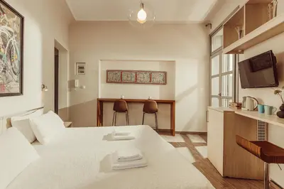 a room with a bed and a table and a kitchen at Suitas in Athens