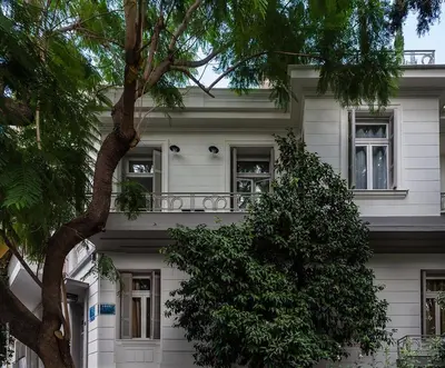 a white house with a tree in front of it at 1930's Athenian House by YHA in Athens