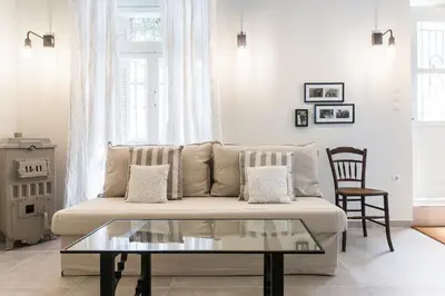 a living room with a couch and a glass coffee table at 1930's Athenian House by YHA in Athens