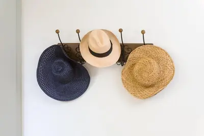 three hats are hanging on a white wall at 1930's Athenian House by YHA in Athens