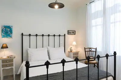 a bedroom with a bed and a chair and a window at 1930's Athenian House by YHA in Athens