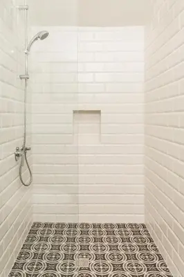 a bathroom with a shower with a tiled floor at 1930's Athenian House by YHA in Athens