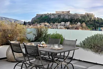 a table and chairs on a balcony with a view of the acropolis at ALTO PSYRRI PENTHOUSE by K&K in Athens