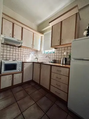 a kitchen with wooden cabinets and a white refrigerator at Cozy Apartments Mc Queen in Athens