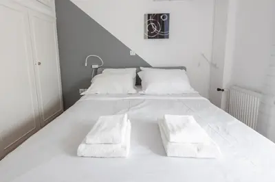 a white bed with two white pillows on it at Deco Marble Apt with Acropolis view in Athens