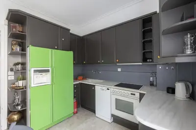 a green refrigerator in a kitchen with black cabinets at Deco Marble Apt with Acropolis view in Athens