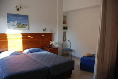 a bedroom with a bed and a chair at Galini Hotel in Agia Marina Aegina