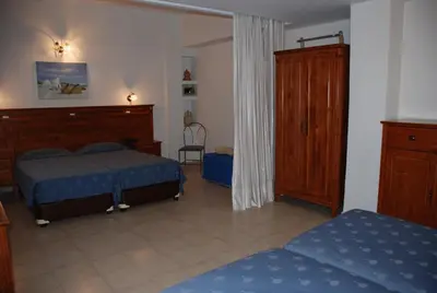 a bedroom with two beds and a dresser at Galini Hotel in Agia Marina Aegina