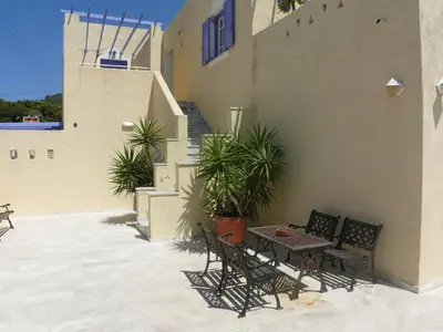 a patio with chairs and a table on a building at Sylvia Studios in Agia Marina Aegina