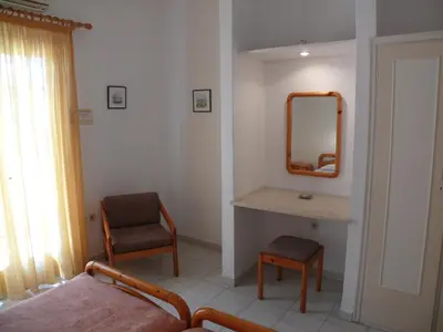 a bedroom with a mirror and a bed and a chair at Sylvia Studios in Agia Marina Aegina