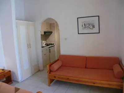 a living room with a couch and a kitchen at Sylvia Studios in Agia Marina Aegina