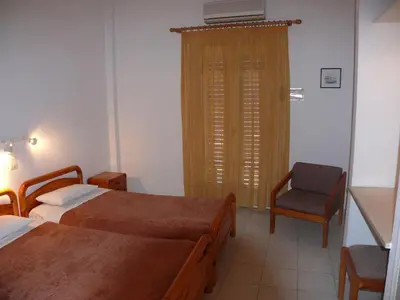 a hotel room with two beds and a chair at Sylvia Studios in Agia Marina Aegina