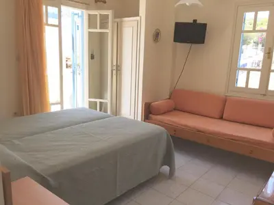 a bedroom with a bed and a couch and a window at Sylvia Studios in Agia Marina Aegina