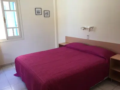 a bedroom with a purple bed with a window at Sylvia Studios in Agia Marina Aegina