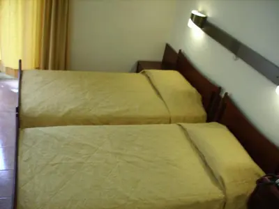 two beds in a hotel room with yellow sheets at Claridge Hotel in Athens
